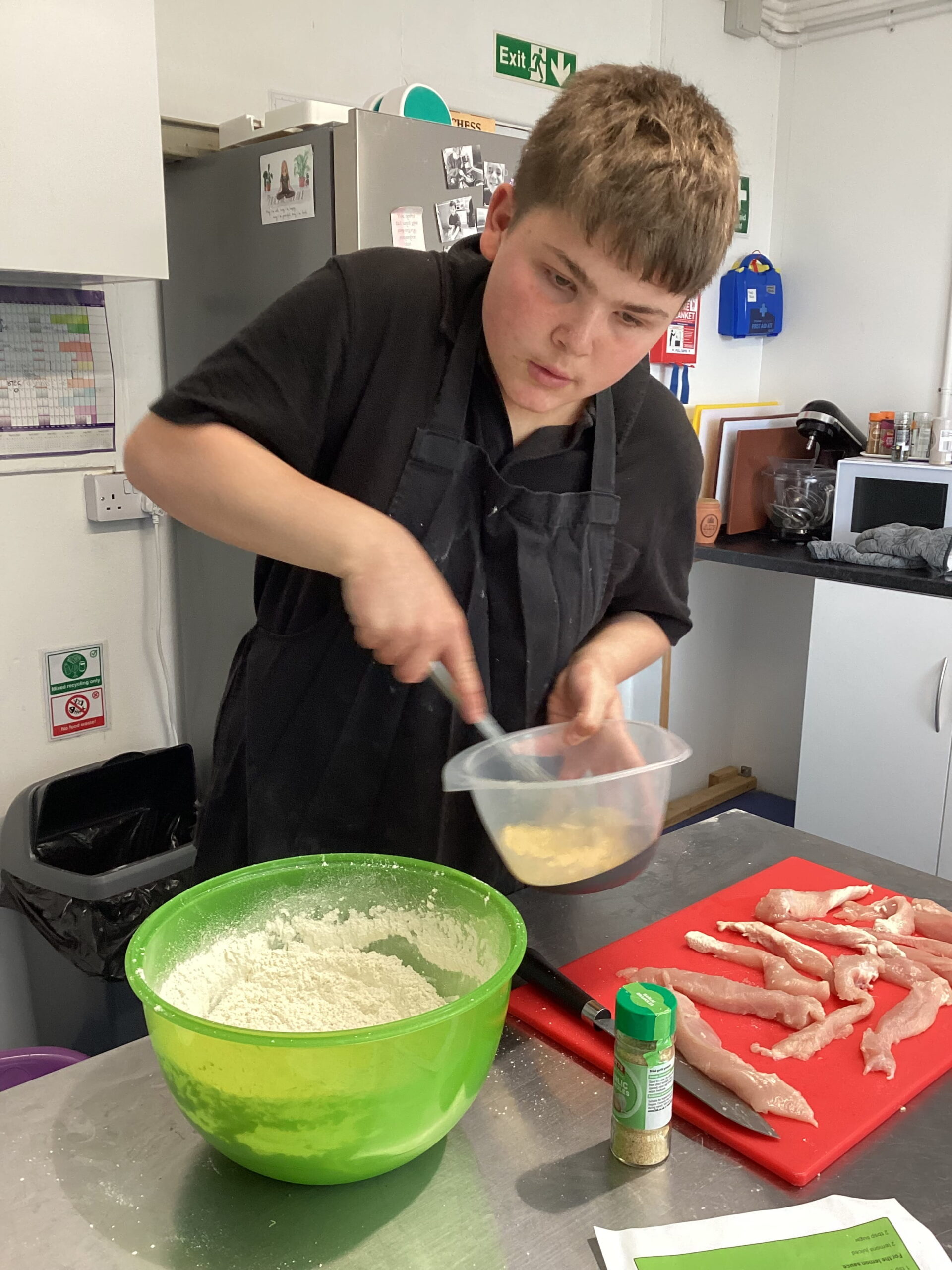 A learner carefully following a recipe as part of their BTEC cooking assessment, demonstrating their food preparation and cooking skills.